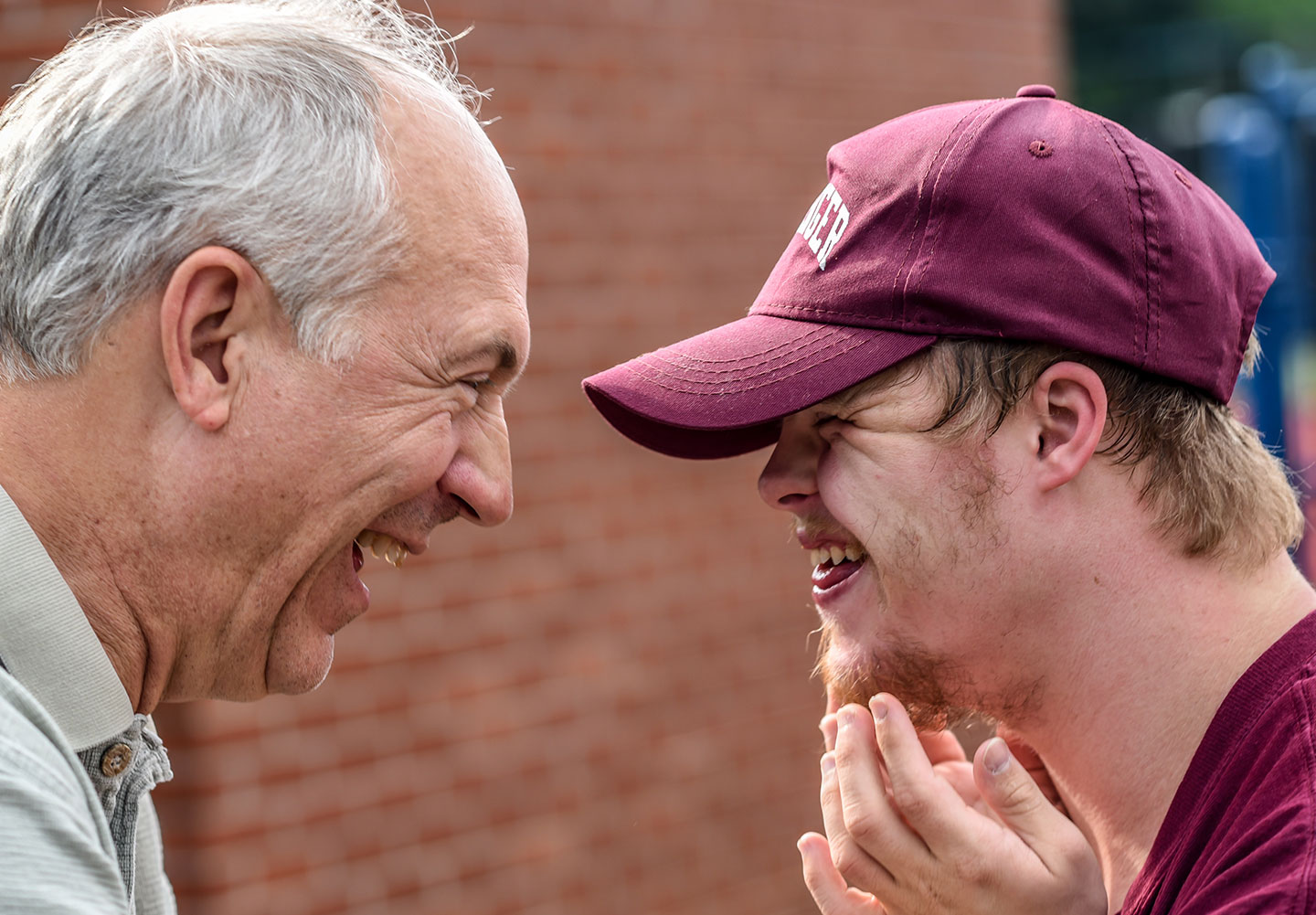 older man laughing with boy with downs syndrome