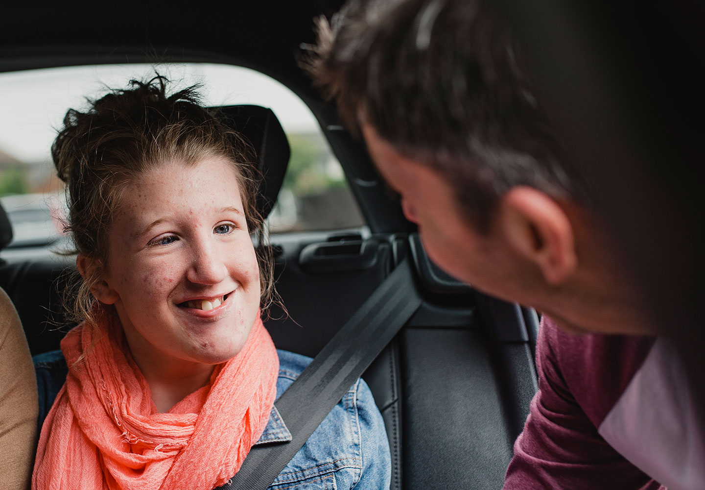 young girl sat in car smiling to dad