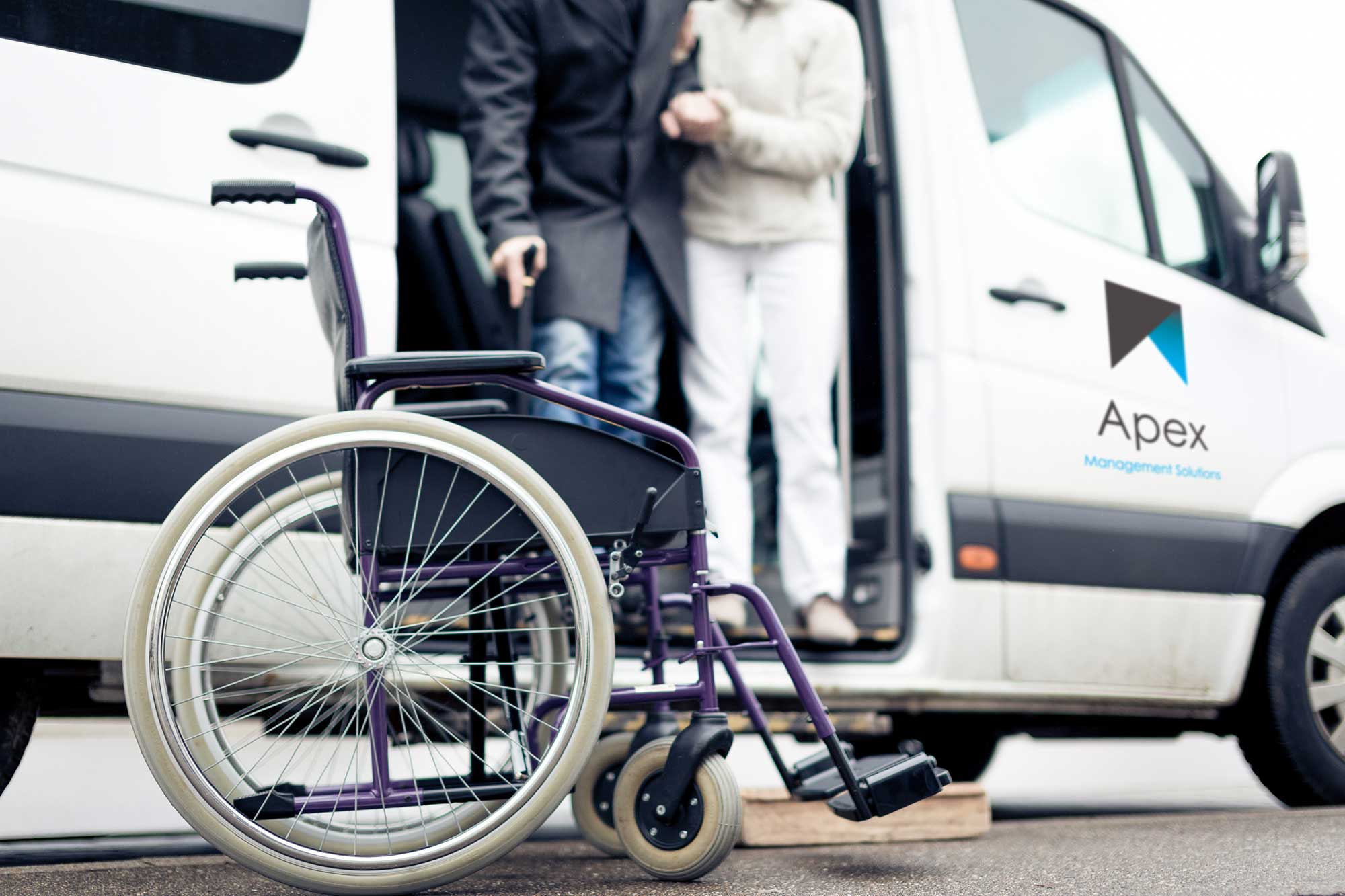 a wheelchair in front of an Apex van